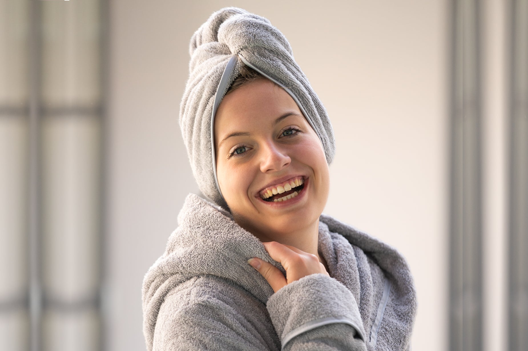 Dieses Bild zeigt eine lächelnde Frau mit einem edlen greuen Bademantel