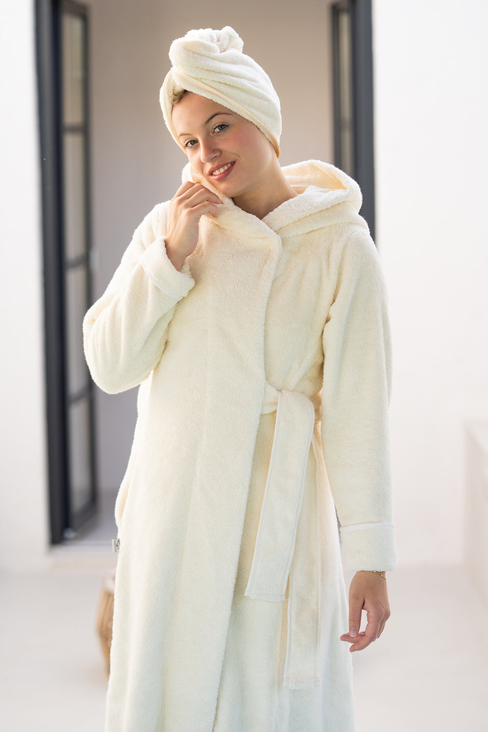Junge Dame im Luxus Bademantel in der Farbe Creme aus nachhaltiger Biobaumwolle mit Kapuze. Seitlich geschnürtem Gürtel. VONNESLHO Design
Extra langer Bademantel für maximalen Komfort